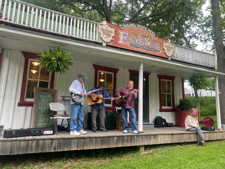 Three banjo players on a porch of the Friends Store in Sang Run, Maryland